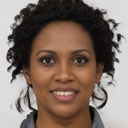 Joyful black young-adult female with long  brown hair and brown eyes