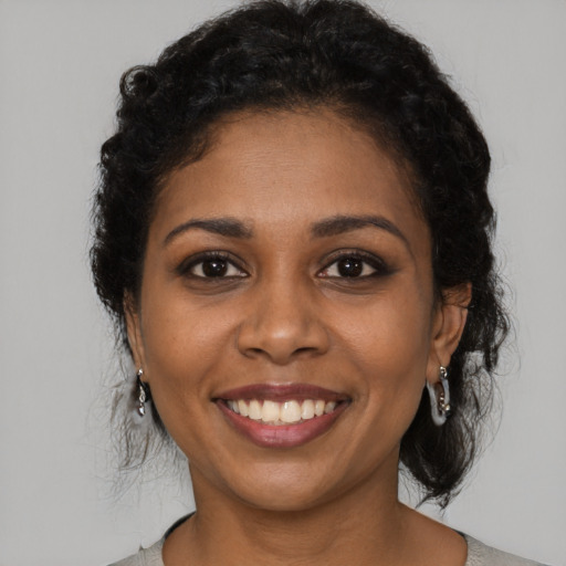 Joyful black young-adult female with long  black hair and brown eyes