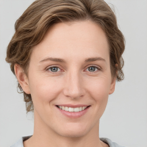 Joyful white young-adult female with medium  brown hair and grey eyes