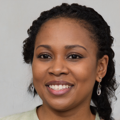 Joyful black young-adult female with long  black hair and brown eyes