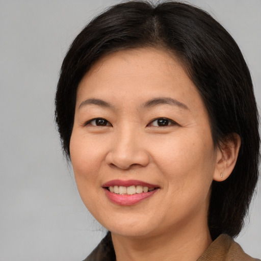 Joyful asian adult female with medium  brown hair and brown eyes