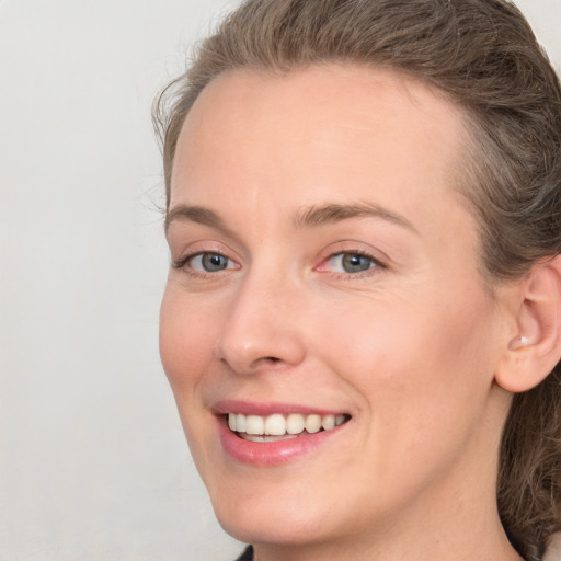 Joyful white young-adult female with medium  brown hair and grey eyes