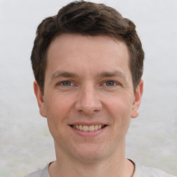 Joyful white young-adult male with short  brown hair and grey eyes