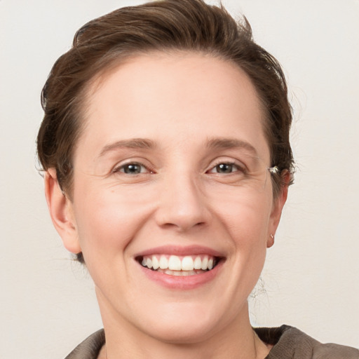 Joyful white young-adult female with medium  brown hair and grey eyes