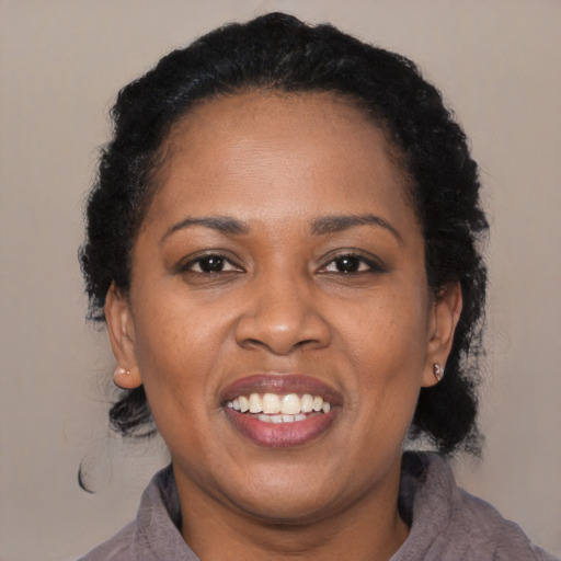 Joyful black young-adult female with long  black hair and brown eyes