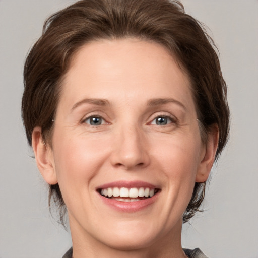 Joyful white adult female with medium  brown hair and grey eyes