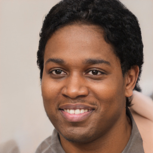 Joyful black young-adult male with short  black hair and brown eyes