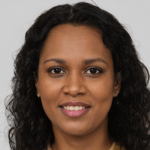 Joyful black young-adult female with long  brown hair and brown eyes