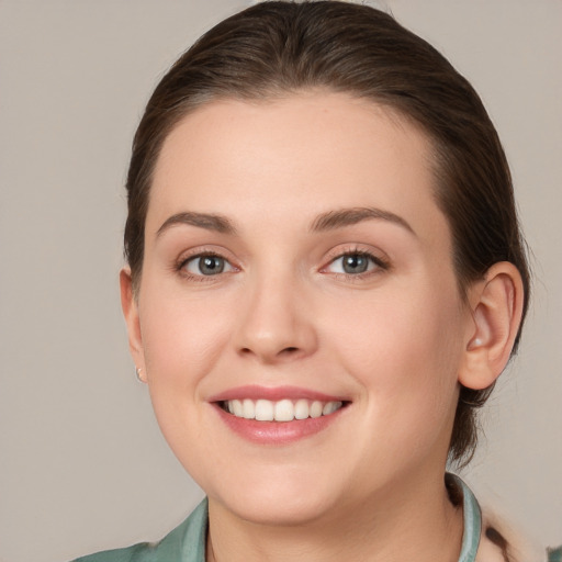 Joyful white young-adult female with medium  brown hair and grey eyes