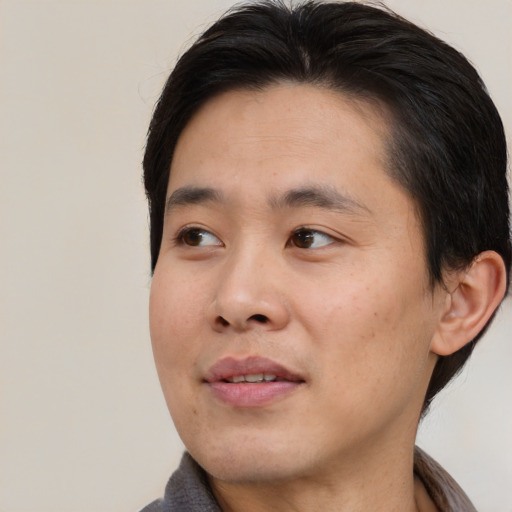 Joyful asian young-adult male with medium  brown hair and brown eyes