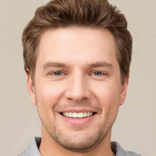 Joyful white young-adult male with short  brown hair and grey eyes