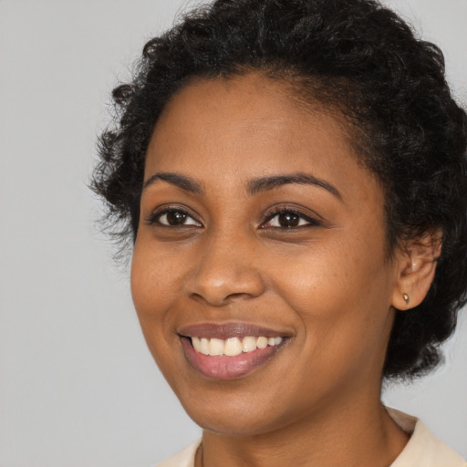 Joyful black young-adult female with short  black hair and brown eyes