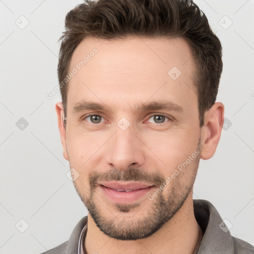 Joyful white young-adult male with short  brown hair and grey eyes