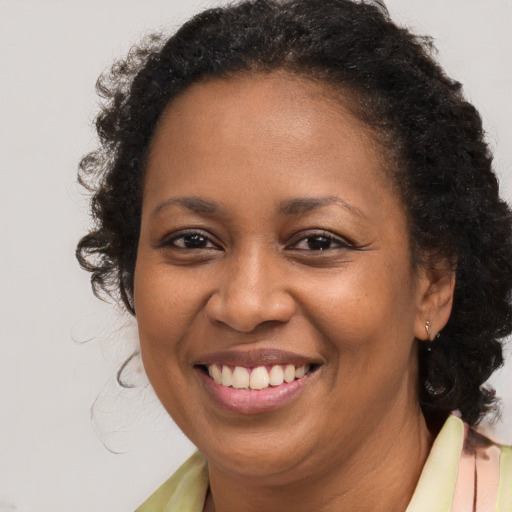 Joyful black young-adult female with long  brown hair and brown eyes