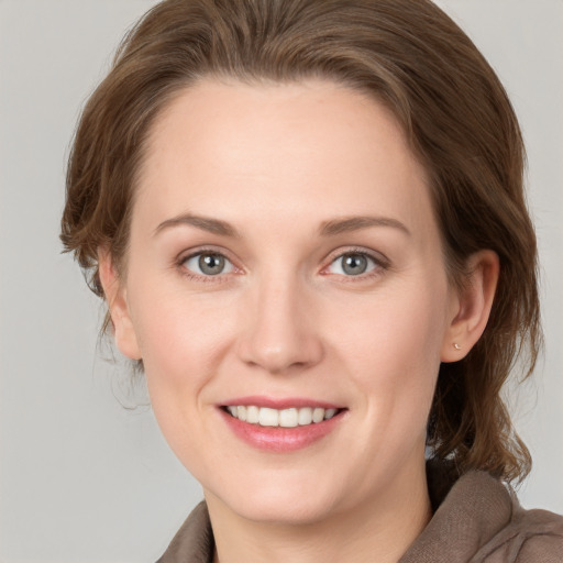 Joyful white young-adult female with medium  brown hair and grey eyes