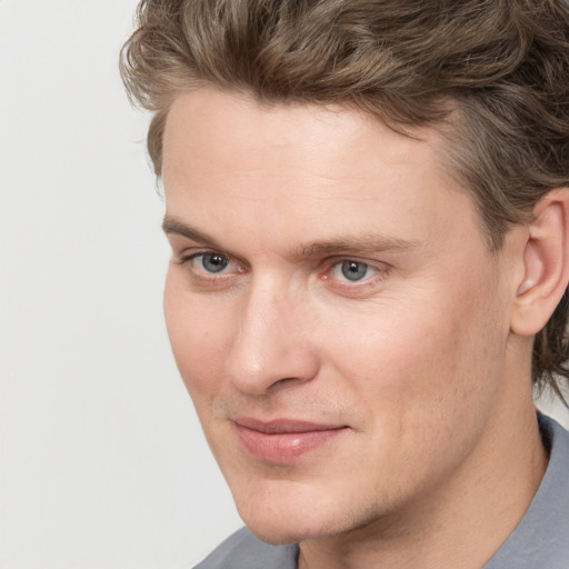 Joyful white young-adult male with short  brown hair and blue eyes