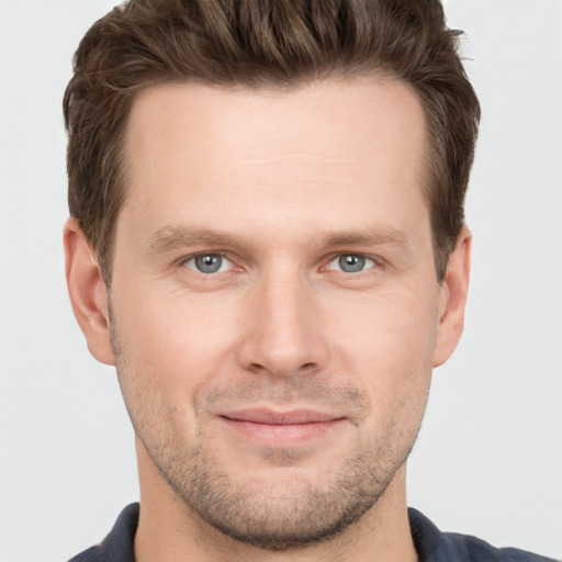 Joyful white young-adult male with short  brown hair and grey eyes