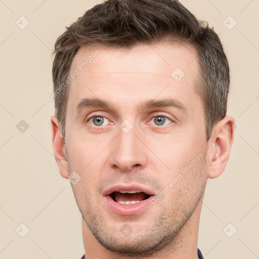 Joyful white young-adult male with short  brown hair and grey eyes