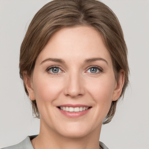 Joyful white young-adult female with medium  brown hair and grey eyes