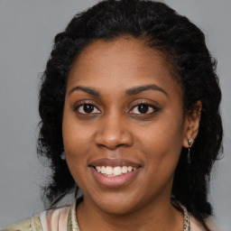 Joyful black young-adult female with long  brown hair and brown eyes