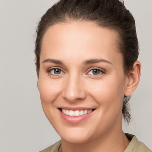 Joyful white young-adult female with medium  brown hair and grey eyes