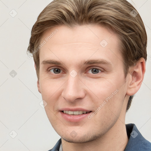 Joyful white young-adult male with short  brown hair and grey eyes