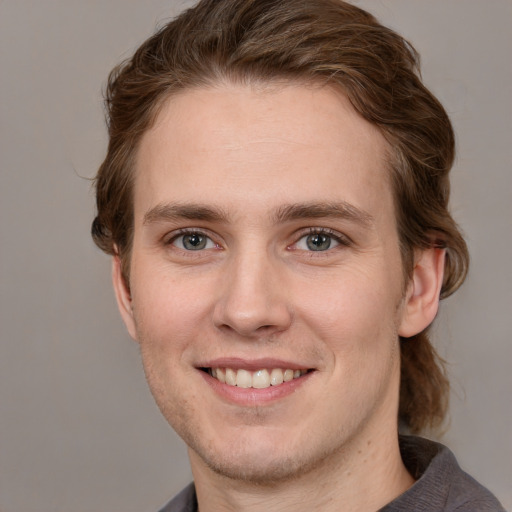 Joyful white young-adult male with medium  brown hair and grey eyes