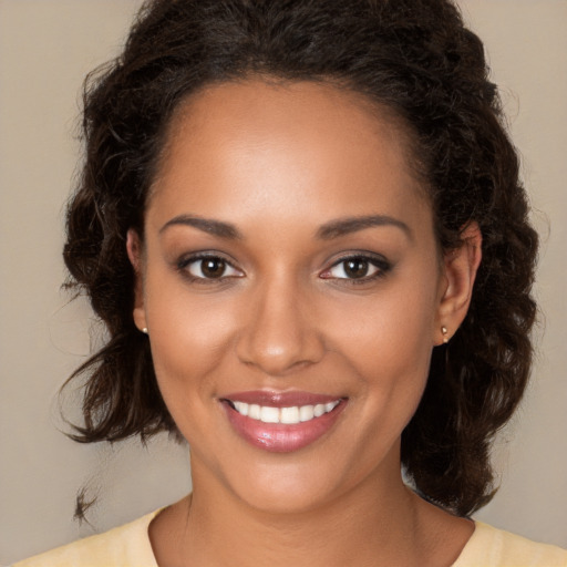 Joyful black young-adult female with long  brown hair and brown eyes