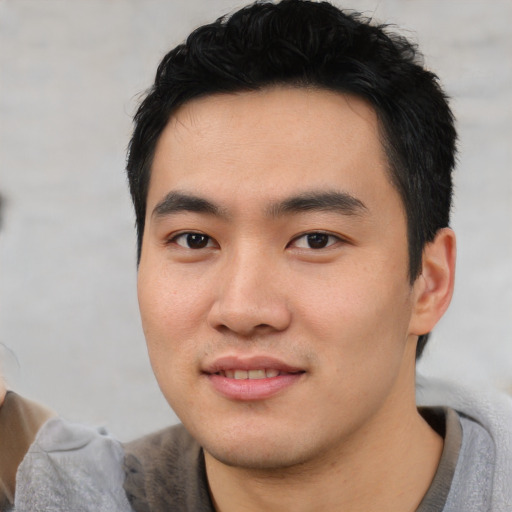 Joyful asian young-adult male with short  black hair and brown eyes