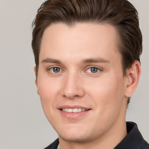 Joyful white young-adult male with short  brown hair and grey eyes