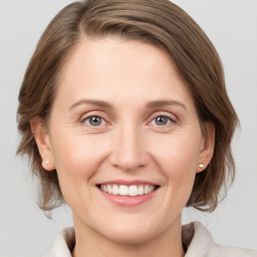 Joyful white young-adult female with medium  brown hair and grey eyes