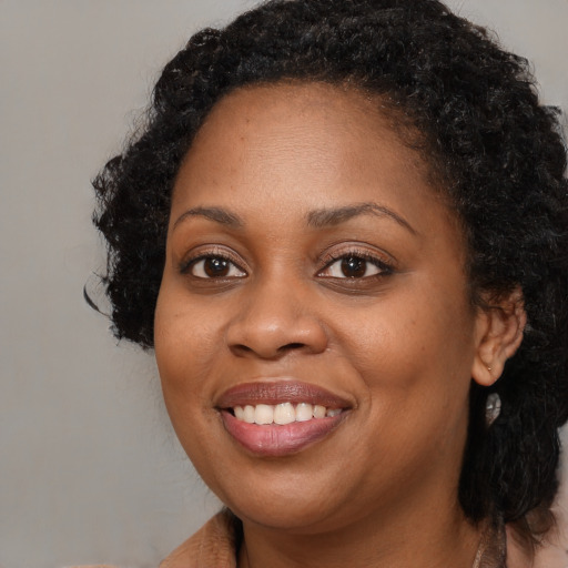 Joyful black young-adult female with long  black hair and brown eyes