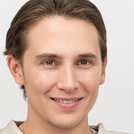 Joyful white young-adult male with short  brown hair and grey eyes