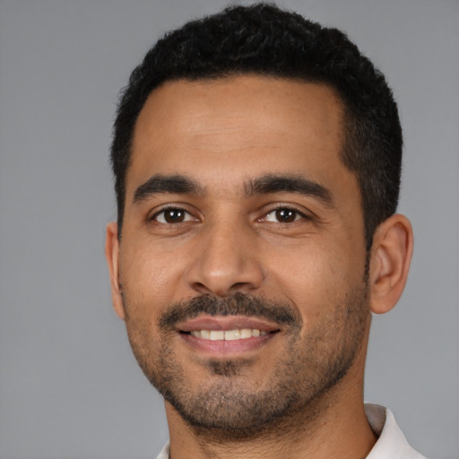 Joyful latino young-adult male with short  black hair and brown eyes