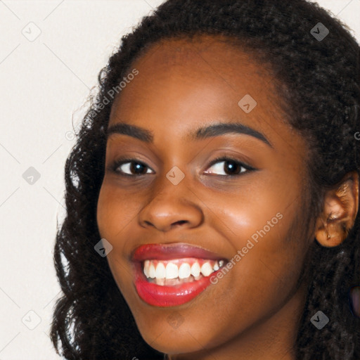 Joyful black young-adult female with long  black hair and brown eyes