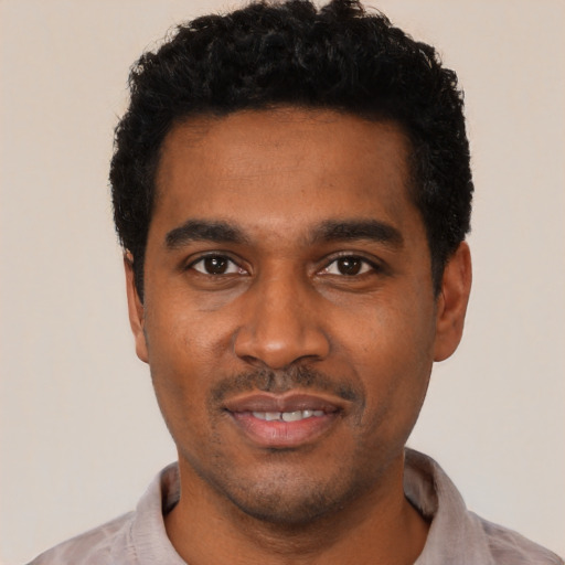 Joyful black young-adult male with short  black hair and brown eyes