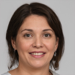 Joyful white adult female with medium  brown hair and grey eyes