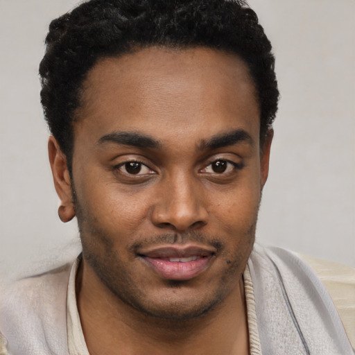 Joyful black young-adult male with short  black hair and brown eyes