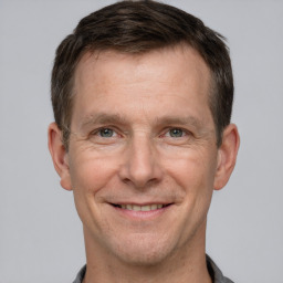 Joyful white adult male with short  brown hair and grey eyes