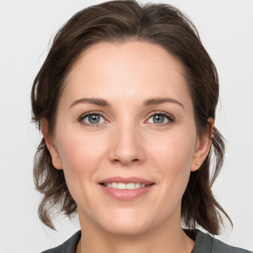 Joyful white young-adult female with medium  brown hair and grey eyes