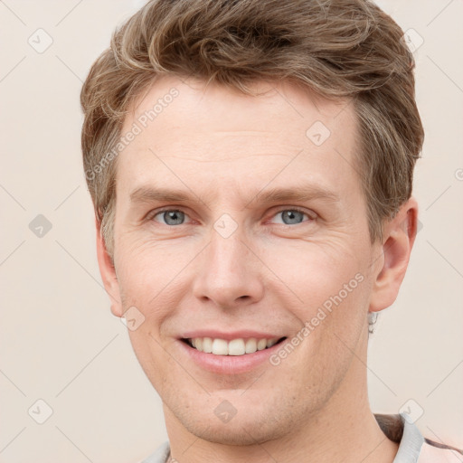 Joyful white young-adult male with short  brown hair and grey eyes