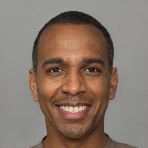 Joyful black young-adult male with short  black hair and brown eyes