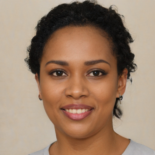 Joyful black young-adult female with short  black hair and brown eyes
