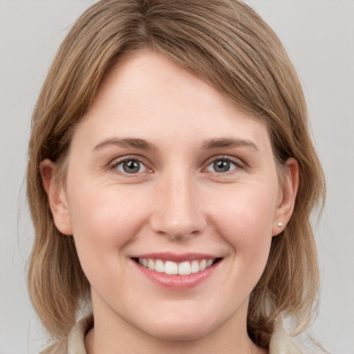 Joyful white young-adult female with medium  brown hair and grey eyes