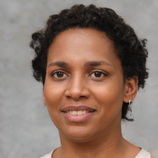 Joyful black young-adult female with short  brown hair and brown eyes