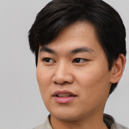 Joyful asian young-adult male with short  black hair and brown eyes