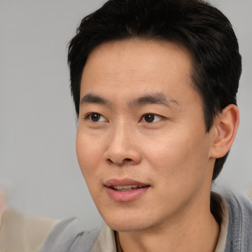 Joyful asian young-adult male with short  black hair and brown eyes