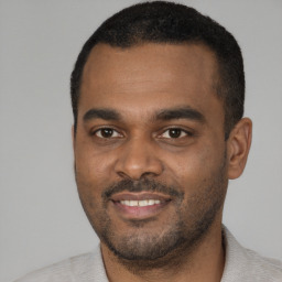 Joyful black young-adult male with short  black hair and brown eyes