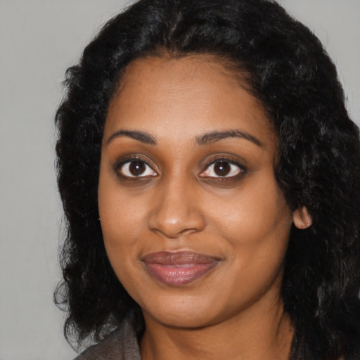 Joyful black young-adult female with long  black hair and brown eyes