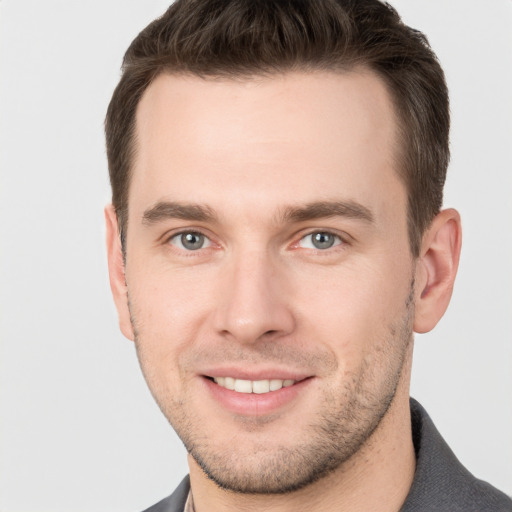 Joyful white young-adult male with short  brown hair and grey eyes